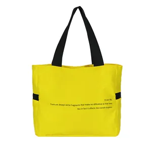 Vista detallada del bolso tote de nailon amarillo con correas negras y cita inglesa