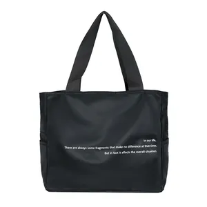 Vista detallada del bolso tote de nailon negro con un diseño de cita minimalista