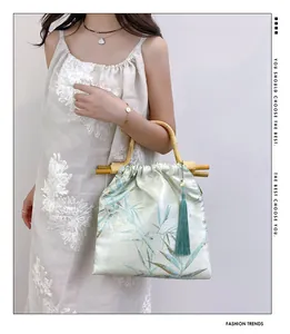 Modella con borsa in stile cinese, manici in bambù e dettaglio nappa verde