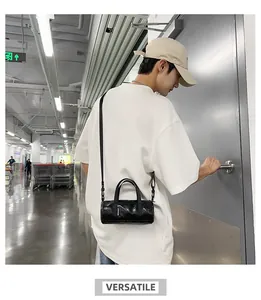 Sleek black mini cylindrical crossbody bag shown on a male model for lifestyle use