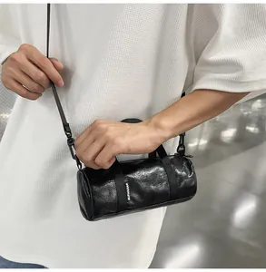 Close-up of mini black cylindrical crossbody bag with textured finish and brand label