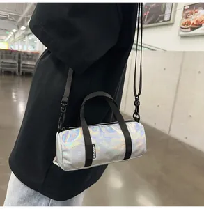 Holographic mini cylindrical crossbody bag with iridescent silver finish and black straps.