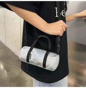 Detail view of a holographic silver mini duffle bag worn crossbody with black straps