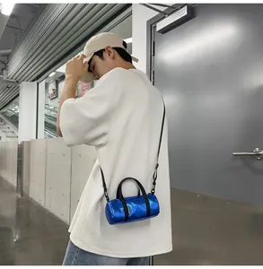Model wearing a mini blue metallic cylindrical crossbody bag in a modern urban setting.