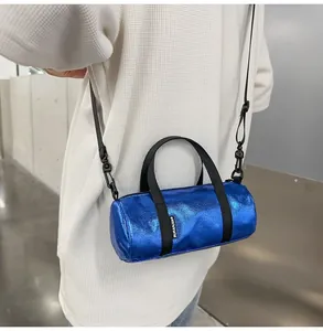 Close-up detail of a vibrant blue metallic cylinder mini crossbody bag with black straps.