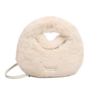 Vista detallada de un bolso de mano de piel sintética beige con una pequeña etiqueta.
