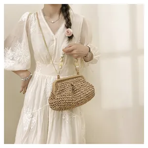 Dettaglio di una pochette in paglia intrecciata con manico di perle e catena d'oro