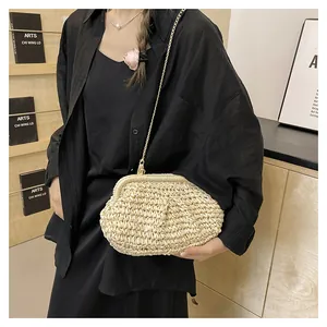 Dettaglio di una pochette in paglia intrecciata a mano con catena a perle dorate