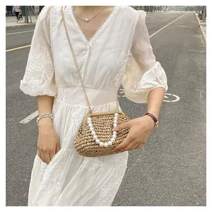Dettaglio della pochette in paglia intrecciata con manico di perle e catena d'oro