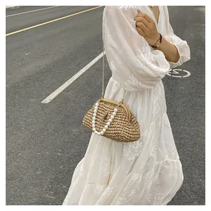 Dettaglio di una borsa da spiaggia in paglia intrecciata con manico di perle e catena d'oro