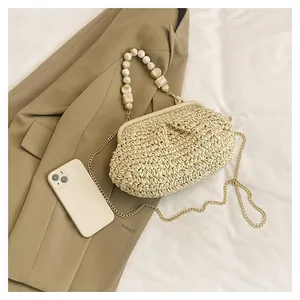Vista lifestyle di una borsa in paglia beige con manico di perle su un blazer elegante.