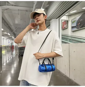 Model wearing a blue metallic mini cylindrical crossbody bag in a street setting
