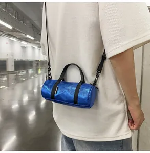 Metallic blue mini barrel crossbody bag worn by a model in a modern urban setting.