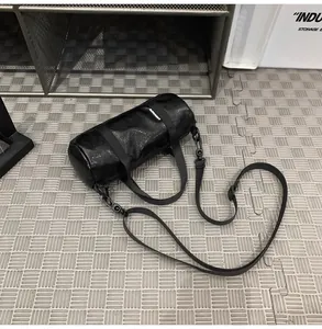 Detail view of mini black cylindrical crossbody bag on industrial floor mat