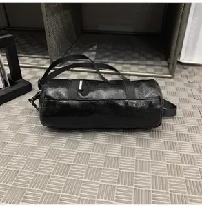 Close-up of a black mini cylindrical crossbody bag with adjustable shoulder strap