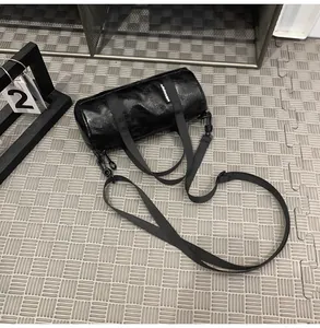 Detailed view of a mini black cylindrical crossbody bag with shiny finish and straps