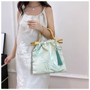 Dettaglio di una borsa in stile cinese con manico in bambù e nappa di seta decorativa