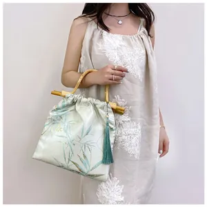 Dettaglio di un'elegante borsa stile neo-cinese con manico in bambù e nappa di seta