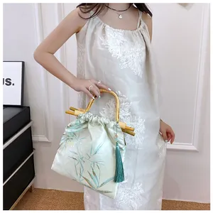 Elegante borsa in stile cinese con manici in bambù e nappa verde portata da una modella.