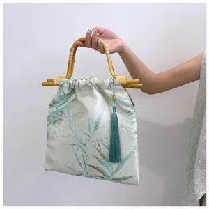 Dettaglio borsa in stile cinese con manico in bambù ed elegante decorazione a nappa.