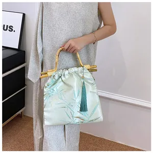 Dettaglio di elegante borsa in stile cinese con manico in bambù e nappa di seta