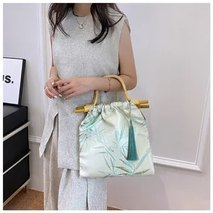 Primo piano di una borsa in stile cinese con manici in bambù e motivi floreali in seta