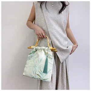 Dettaglio della borsa in stile cinese moderno con manico in bambù e nappa blu.