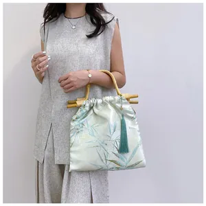 Modella con borsa cinese vintage con manici in bambù e nappa verde decorativa
