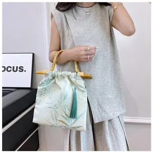 Dettaglio di una borsa retrò in stile cinese con manico in bambù e nappa.