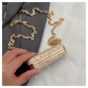 Close-up of a sparkling gold glitter mini lipstick bag with a gold chain strap