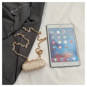 Detailed view of a silver glitter mini evening bag with gold chain next to a tablet