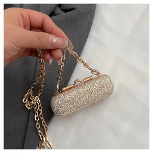 Close-up detail of a glittering gold mini lipstick bag with a stylish chain strap.