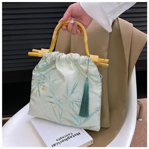 Dettaglio elegante borsa a mano verde chiaro con manico in bambù e nappa