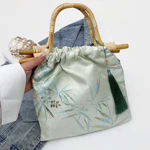 Vista dettagliata di una borsa stile cinese verde chiaro con manici in bambù e nappa
