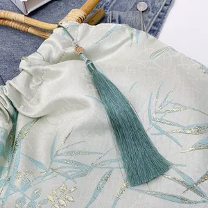 Dettaglio di una borsa in stile cinese con nappa verde acqua e manico in bambù