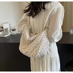 Detalle de un bolso bandolera blanco con estampado de flores llevado por una modelo.