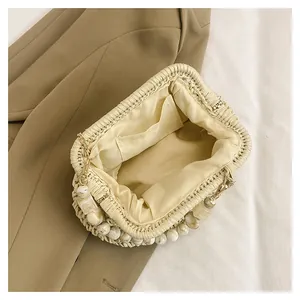 Primo piano del vano interno e del manico di perle di una borsa a mano in paglia