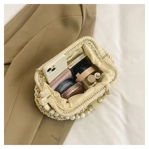 Dettaglio interno di una borsa chic in paglia intrecciata con perle e cosmetici.