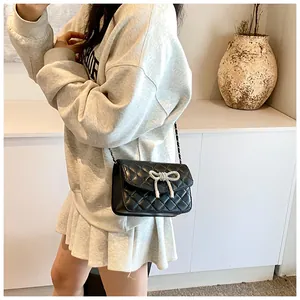 Detail van een zwarte gewatteerde crossbodytas met een zilveren strik op een model
