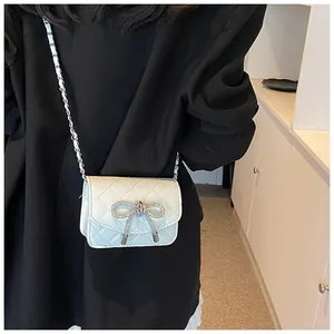 Elegante witte gewatteerde minitas met een strik van strass en een kettingriem.