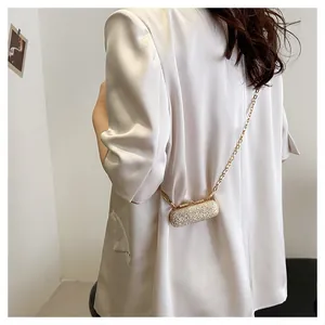 Detailed close-up of a gold glitter mini lipstick bag with chain strap on a white blazer