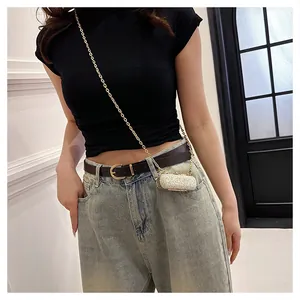Detail showing a stylish glittery mini lipstick bag with a gold chain strap on a model.