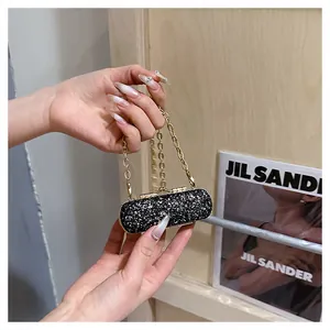 Close-up of a sparkling black mini sequin lipstick bag with an elegant gold chain strap