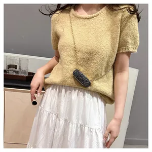 Mini sequined lipstick bag with gold chain worn across a knit sweater