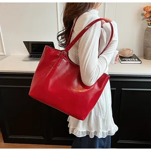 Elegant red glossy leather tote bag carried by model in a stylish office environment