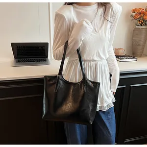 Model carrying a black high-end minimalist tote bag in a lifestyle office setting