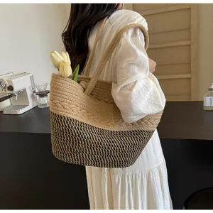 Détail d'un sac cabas en paille tressée avec des tulipes porté par un mannequin en café