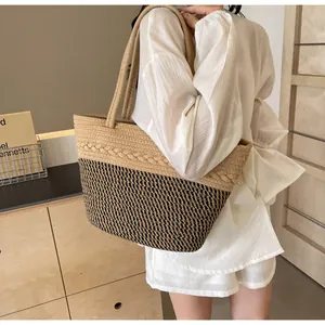 Sac fourre-tout en paille tissée avec bandoulières porté par un mannequin en blanc