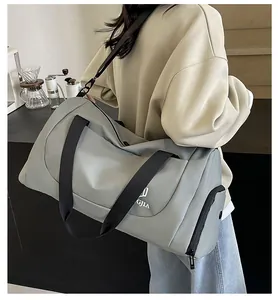 Detail shot of a large gray duffel bag carried by a model in a cafe-style background