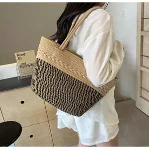 Grand sac cabas bicolore en paille tressée porté par un mannequin en studio